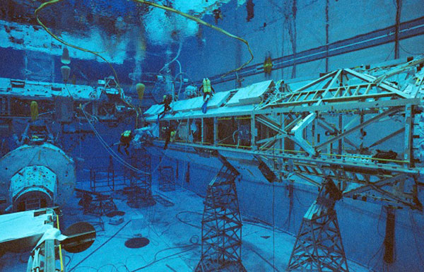 NASA astronaut Robert Curbeam, Jr. and European Space Agency astronaut Christer Fuglesang, wearing training versions of the EMU (in white), participate in an underwater EVA training exercise in NASA's Neutral Buoyancy Laboratory in preparation for the STS-116 mission